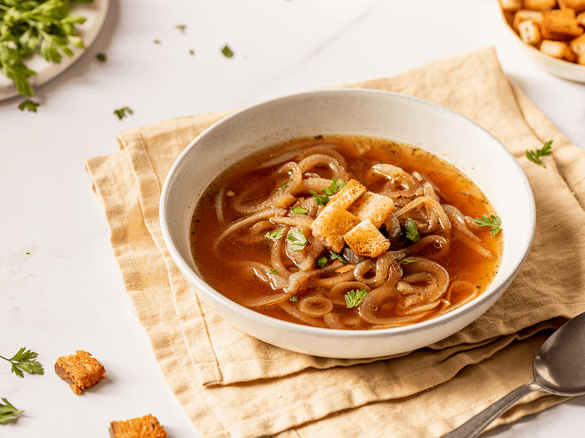 Savory onion soup in a serving bowl topped with croutons.
