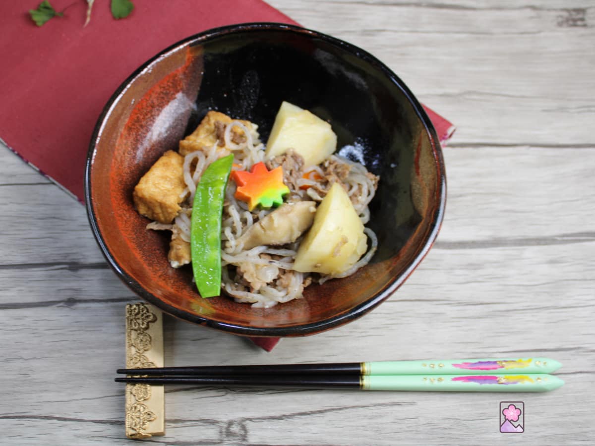 Nikujaga, stewed meat and potatoes, served in a beautiful glazed clay bowl with a set of chopsticks nearby