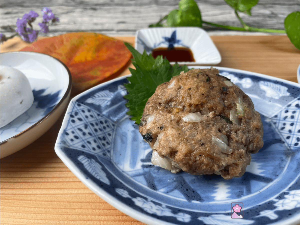 A delicious Baked Okara burger sits on a shiso leaf atop a ceramic dish