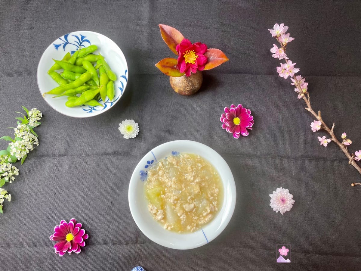 Chicken and Daikon Radish stew served in a Japanese ceramic bowl with a bowl of fresh edamame in the background.