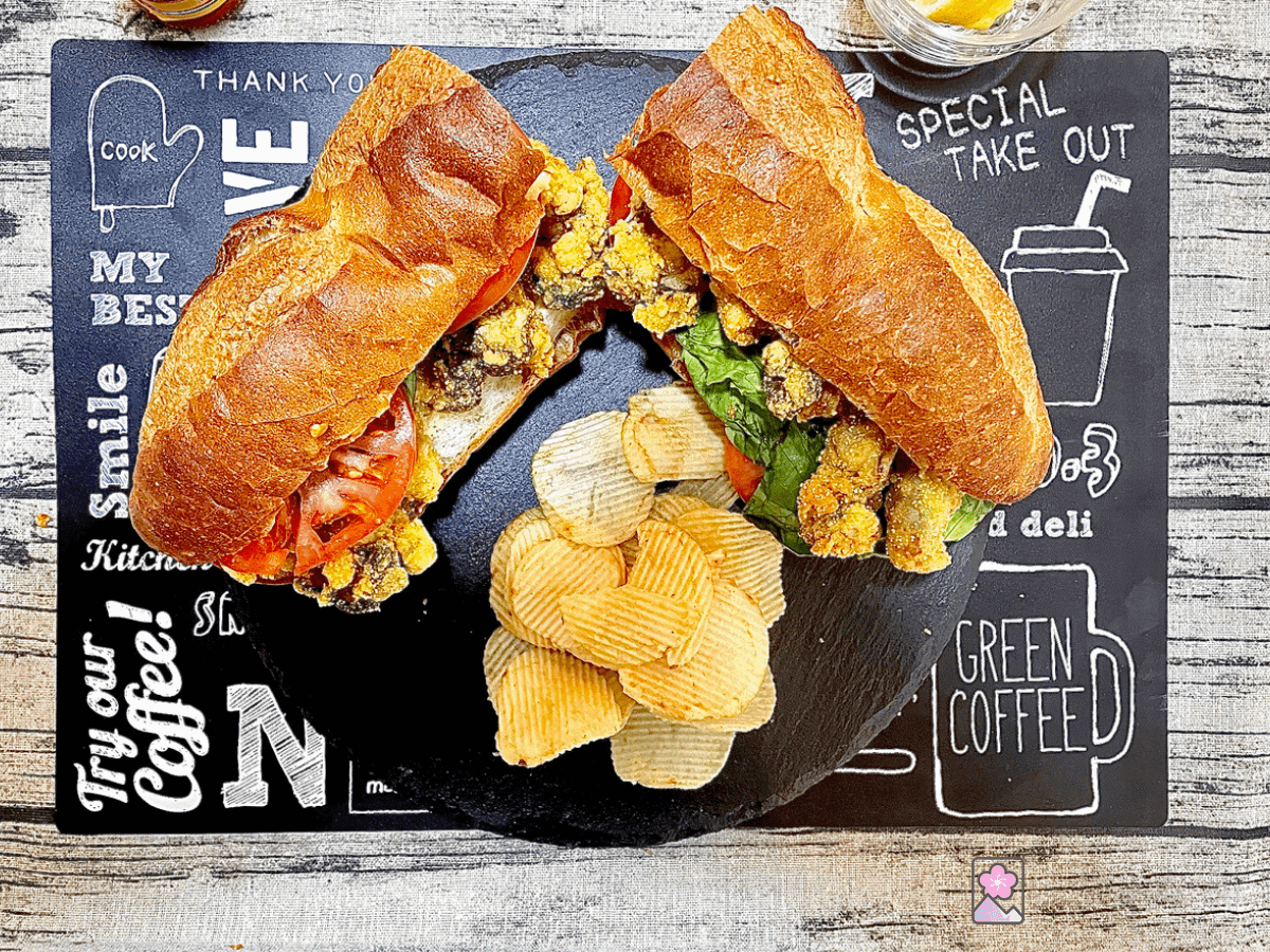 An Oyster Po’ Boy served on French Bread on a Slate plate with potato chips on the side