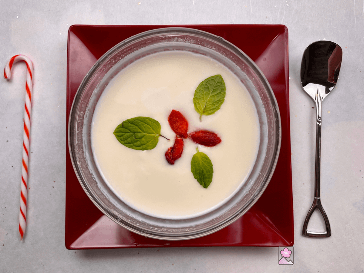 Annin Tofu- pudding with red goji berries and green spearmint leafs on top in a glass bowl.