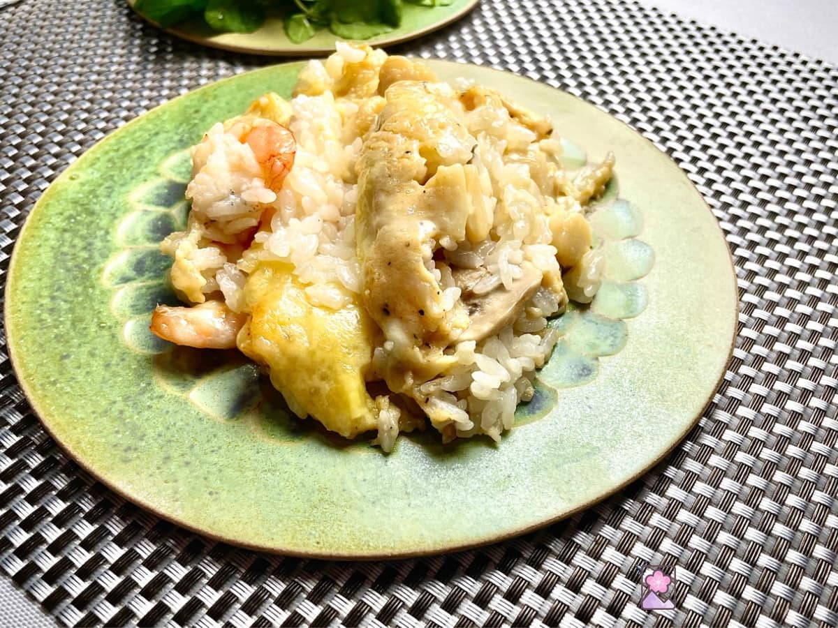 Seafood Doria on a green ceramic plate on a woven placemat with a watercress salad in the background