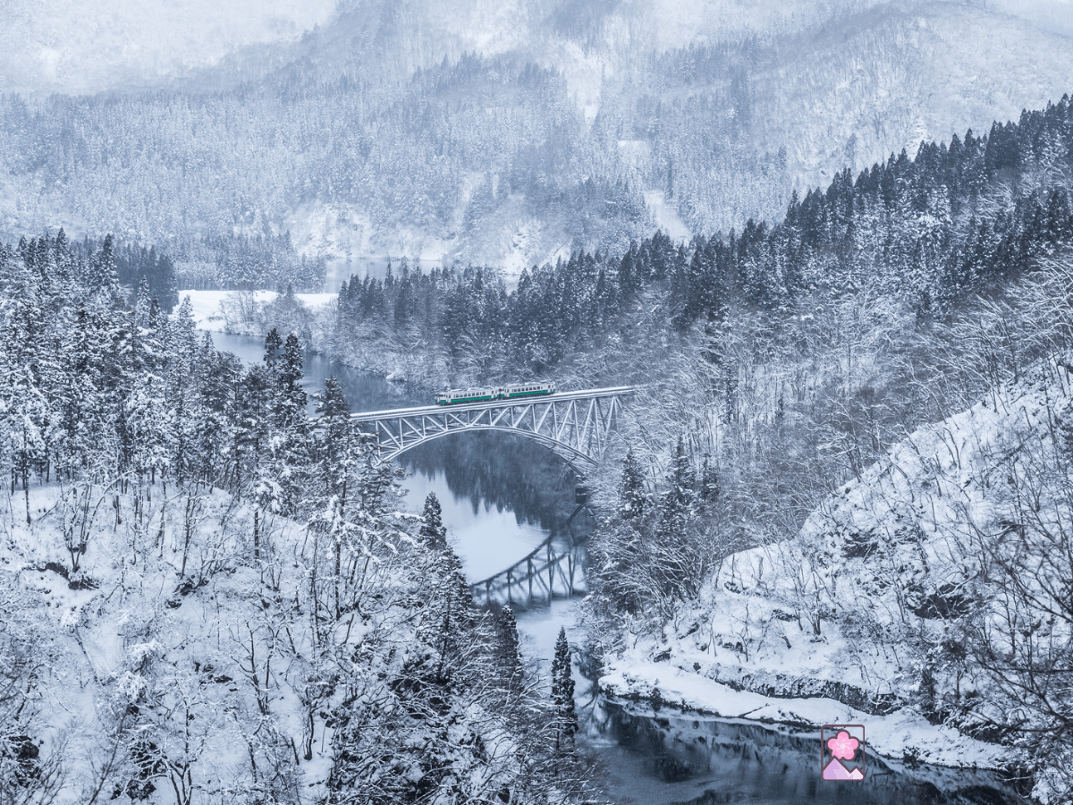 A train crosses a snow covered gorge on the Tadami Railway Line