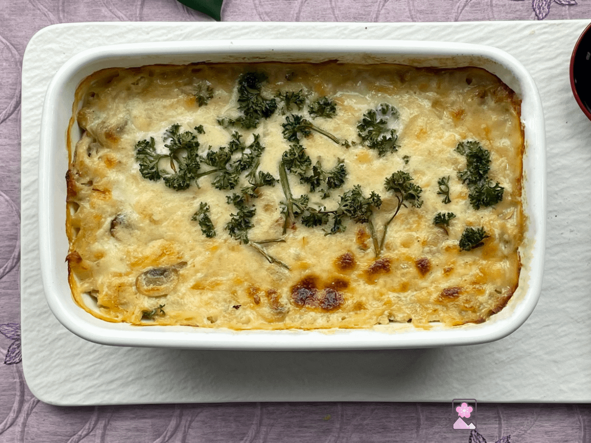 Japanese Style Crab Gratin with Shredded Potatoes baked in a casserole dish on a white ceramic tray.