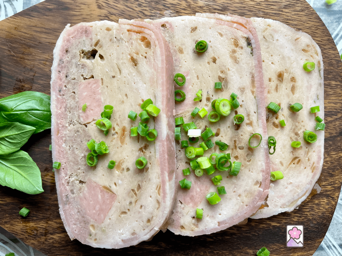 Slow Cooker Chicken and Pork Terrine Sliced into three thin slices to—Ed with finely chopped scallions in a small wooden cutting board.