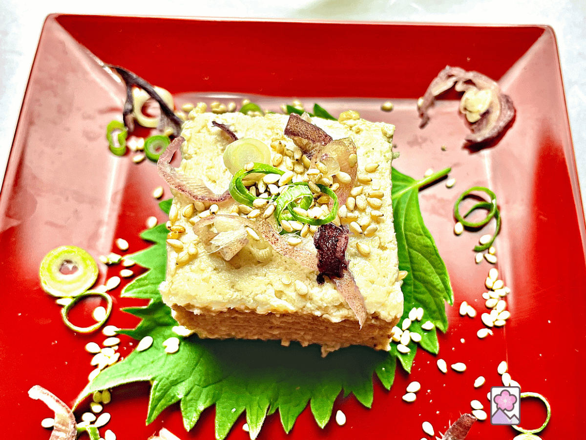 Goma tofu topped with Scallions, Myoga and sesame seeds on a shiso leaf