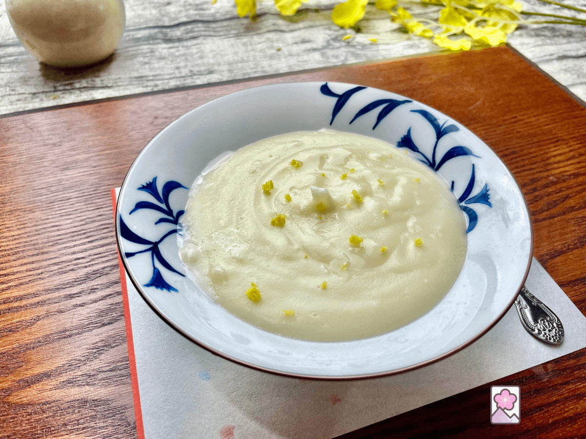 Lemon Kudzu pudding in a ceramic bowl, topped with lemon zest