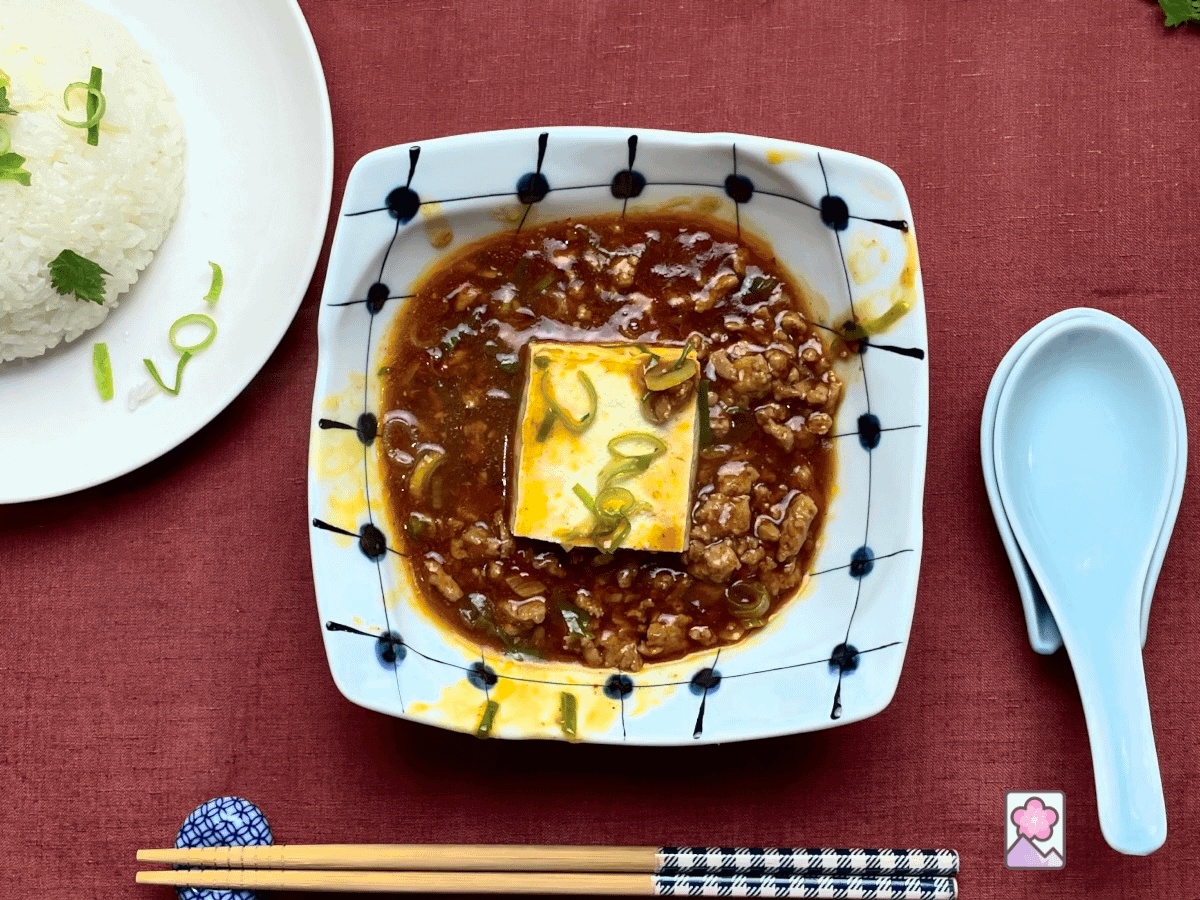 Savory and Spicy Tofu in XO Sauce features a piece of Tofu surrounded by spicy XO sauce with steamed rice behind.