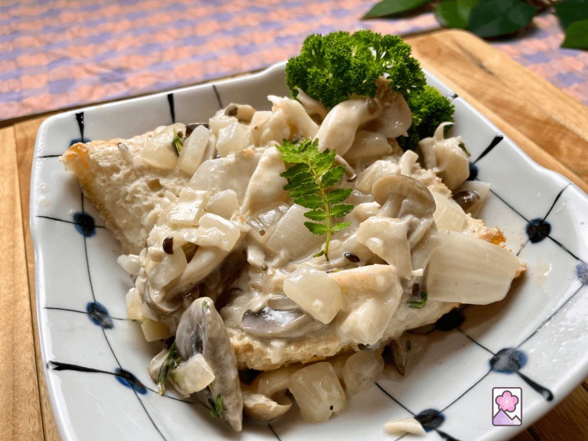 Savory Mushroom Fricassée served over a toasted baguette in a ceramic bowl.