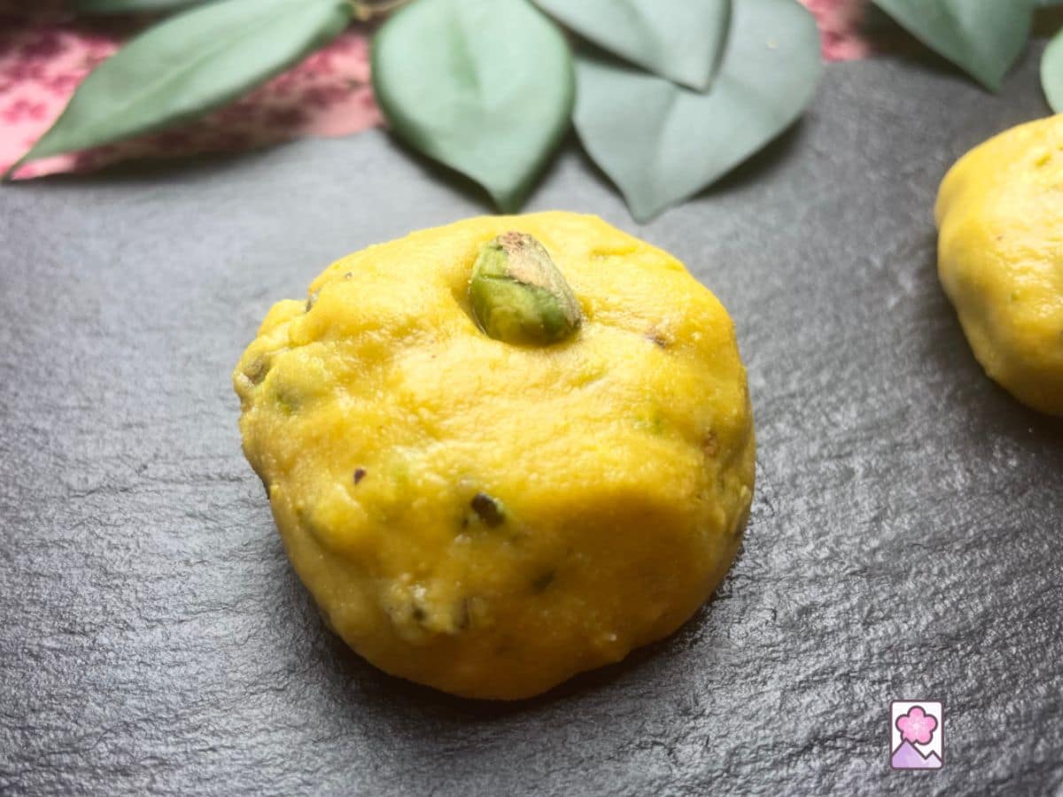 A Temple Laddu on a slate tray topped with a shelled pistachio nut