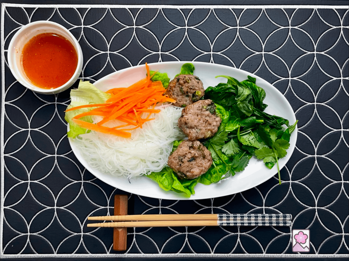 Savory Vietnamese Meatballs served with rice noodles on a bed of lettuce with zesty dipping sauce on the side.