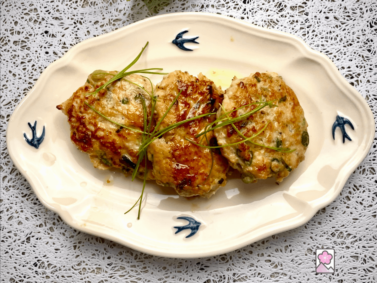 Three Hiroshima Maple chicken sausage patties lined up on a plate and topped with chives