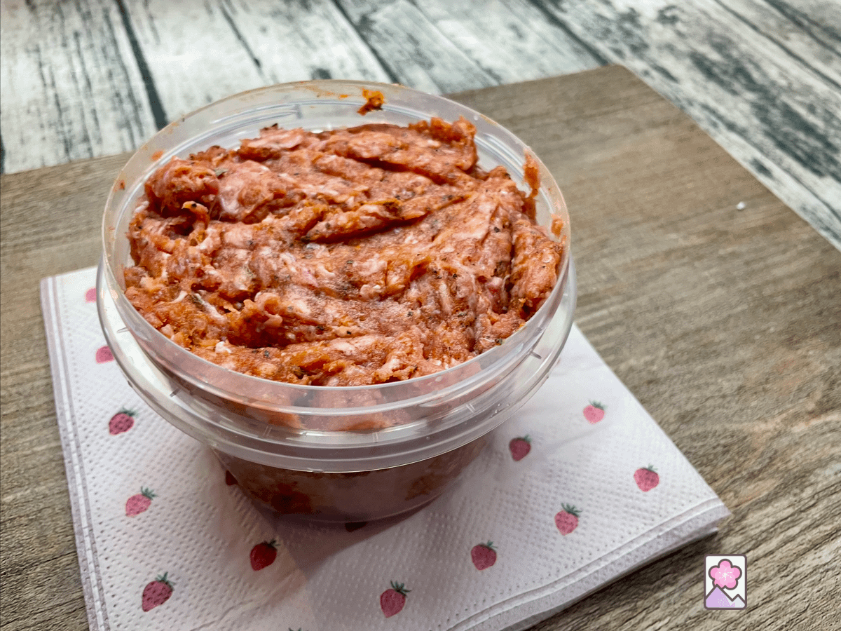 Savory homemade Italian sausage meat in a cylindrical plastic container is ready for refrigeration or freezing