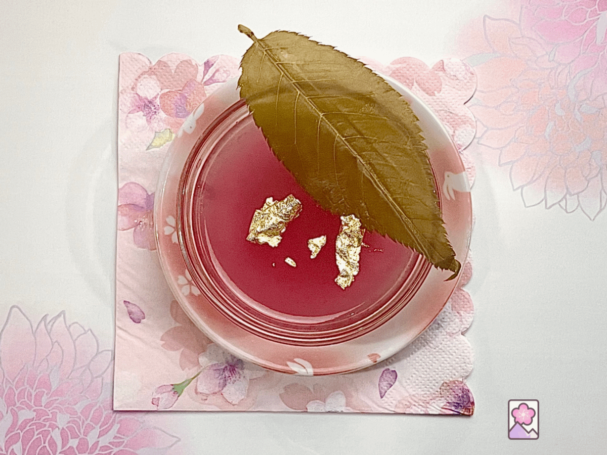 Sakura Gelatin in a glass bowl topped off with gold leaf and a pickled cherry leaf