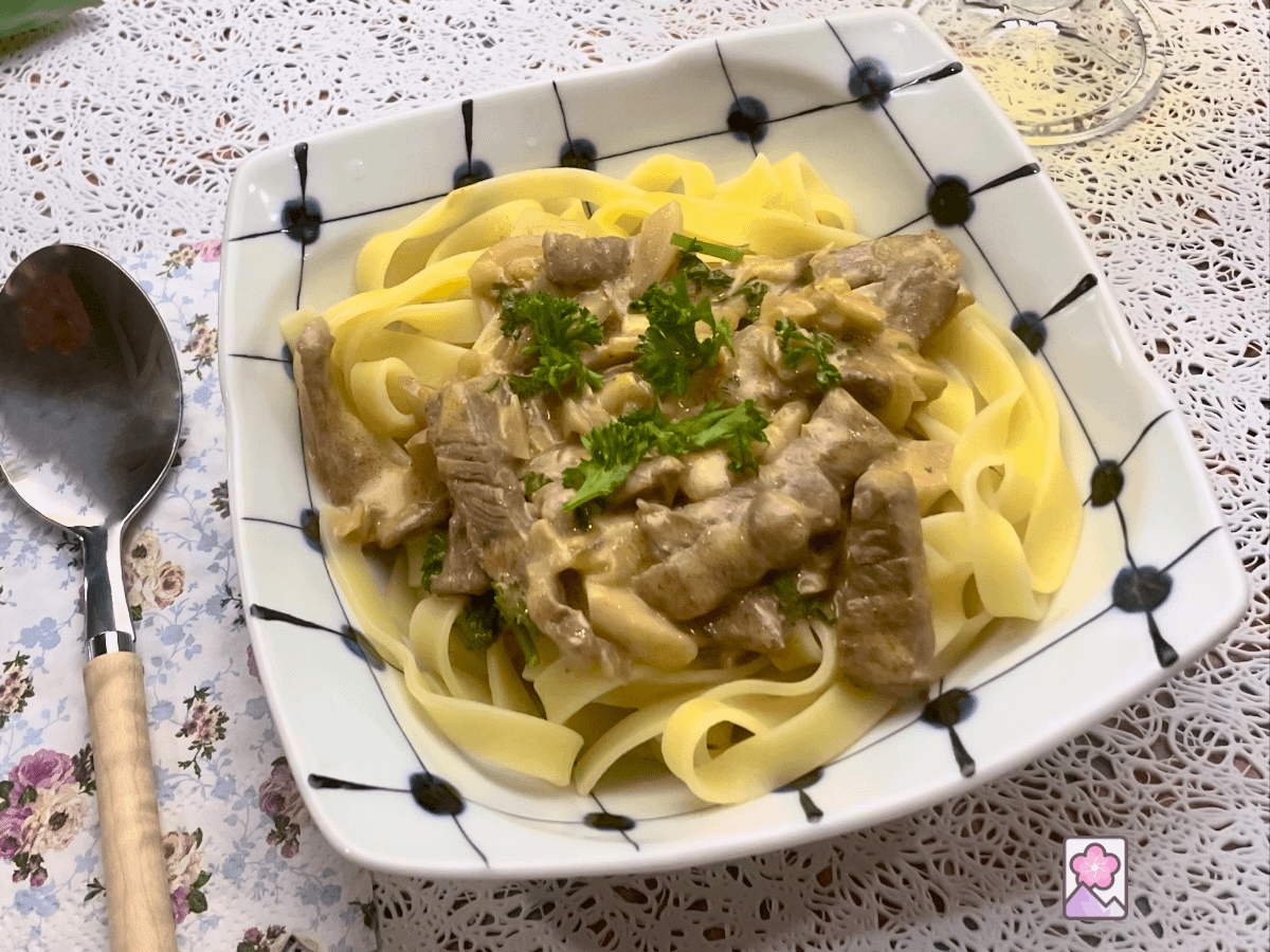 Wagyu Stroganoff served over flat noodles in a ceramic bowl