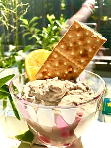 A scoop of smoked bonito dip in a serving bowl with a cracker and garnished with lemon