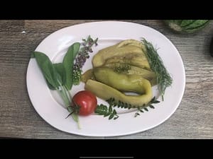 Marinated eggplant arranged on a plate with herbs and flowers
