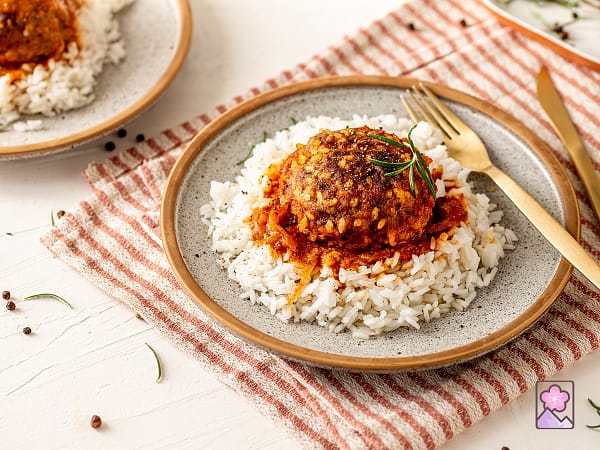 A Salisbury Steaks on white rice and plated on a ceramic dish