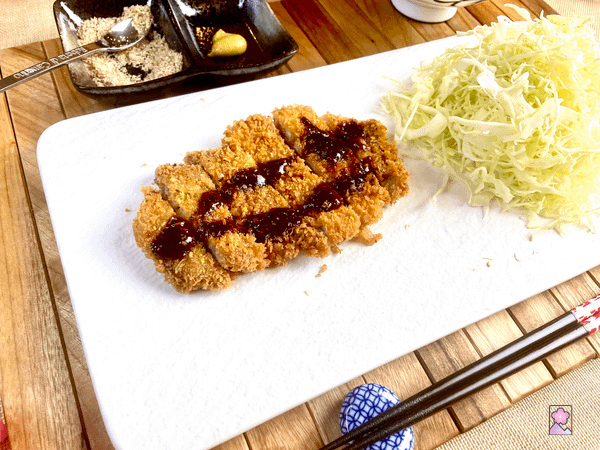 Tonkatsu on a white rectangular There is another bowl on the top right with only the base in view and we can’t tell what’s inside.