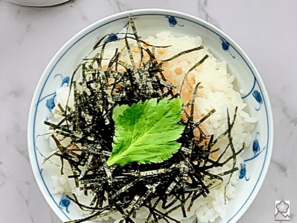 White rice to—Ed with Arare, nori and sesame with a fresh mitsuba leaf on top