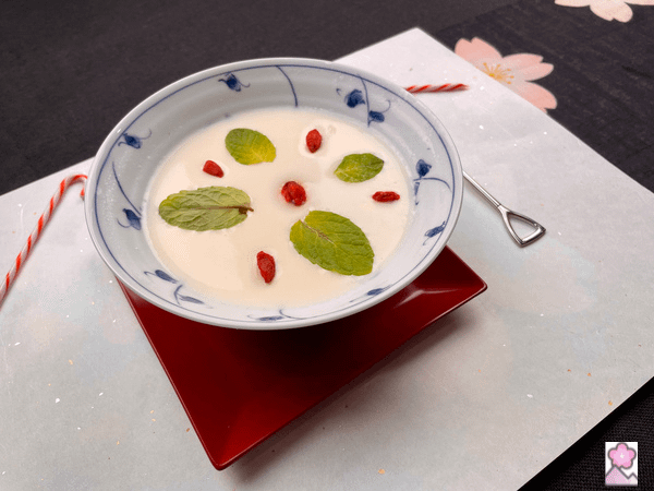 Annin tofu in a ceramic bowl topped with berries and mint leaves