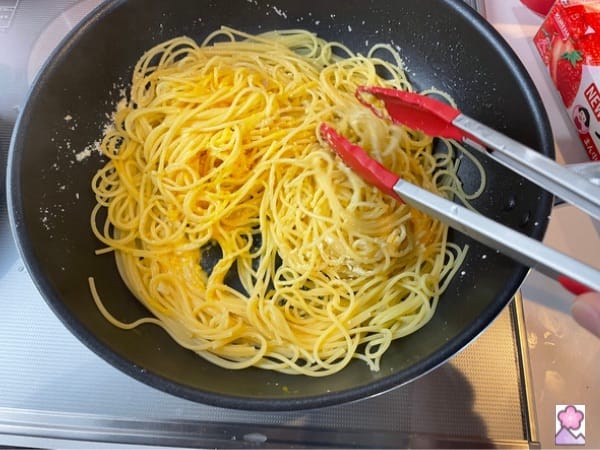 Mixing pasta in the sauté pan with creamy ingredients