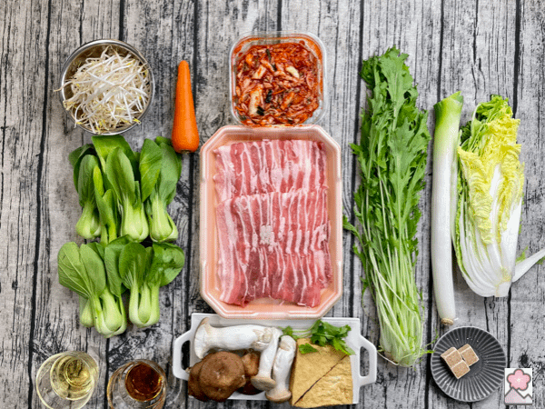 All the ingredients for Kimchi nabe laid out on a wooden table