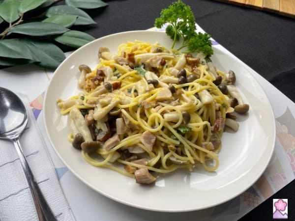 Bacon Kinoko pasta in cream sauce served On a white plate with a parsley sprig