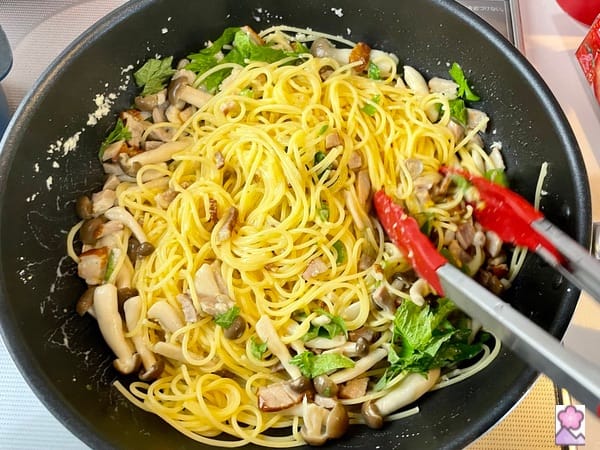 Stirring the bacon and Kinoko in with the pasta in a saucepan