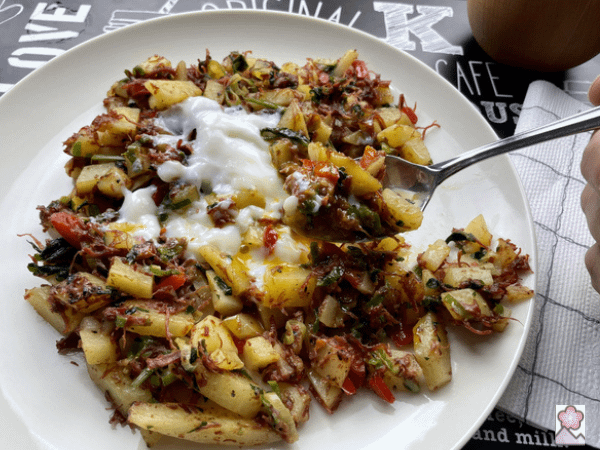 Savory Corned Beef Hash topped with a poached egg Which is mixed into the hash.