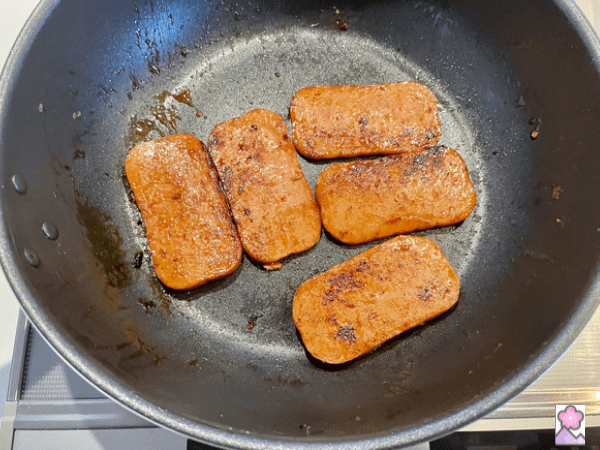5 slices of fried spam in a saucepan