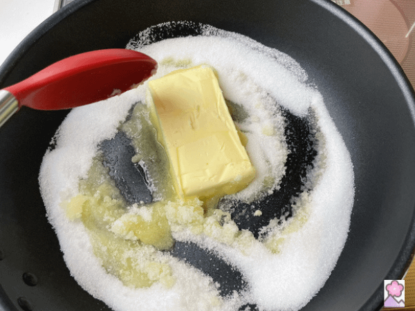 Sugar and butter in a pan. The butter is melting and being stirred in with the sugar.