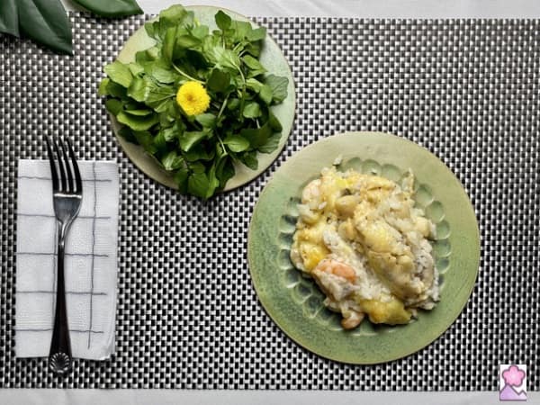 Seafood Doria on a plate with a watercress salad on a smaller plate