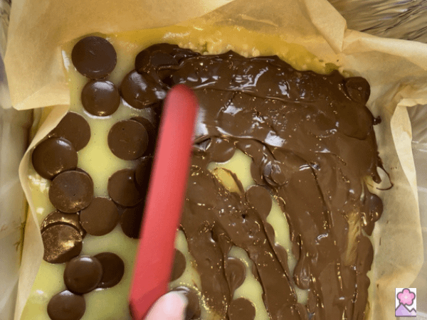 Spreading melted chocolate over the toffee with a flat spatula