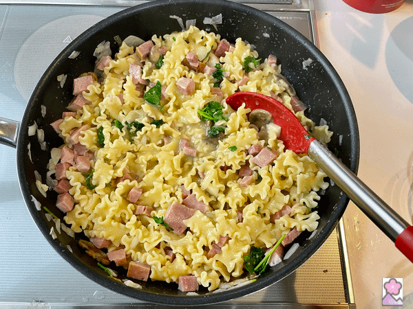 Tetrazzini in the frypan being stirred with a large kitchen spoon