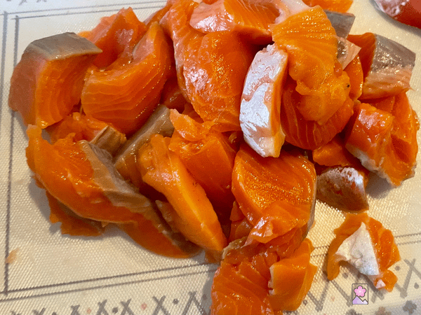 Salmon diced into 1 inch pieces on a cutting board