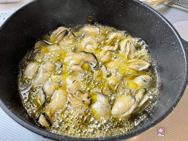 Oysters in a frypan cooking in olive oil