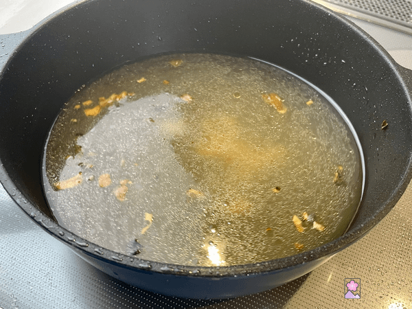 Consommé with bits of garlic and mushroom in a cooking pot