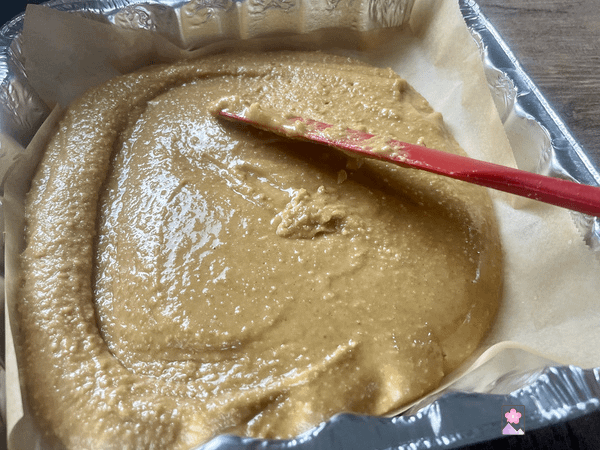 Spreading the peanut butter bar mix in a foil pan