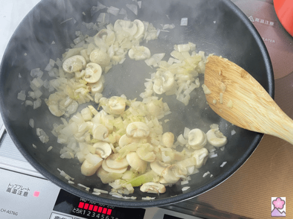 Onion celery and mushrooms sautéed with butter flour and salt and pepper in a metal pan being stirred with a wooden spoon