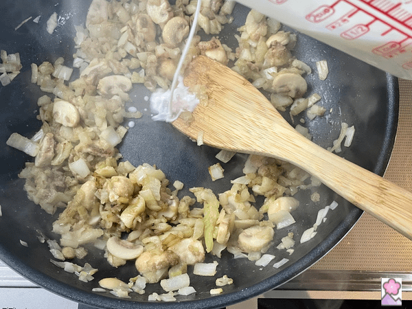 Adding milk to vegetables and flour while in a sauté pan