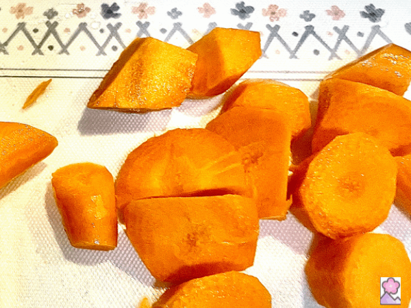 Carrots chopped into chunks on a cutting board