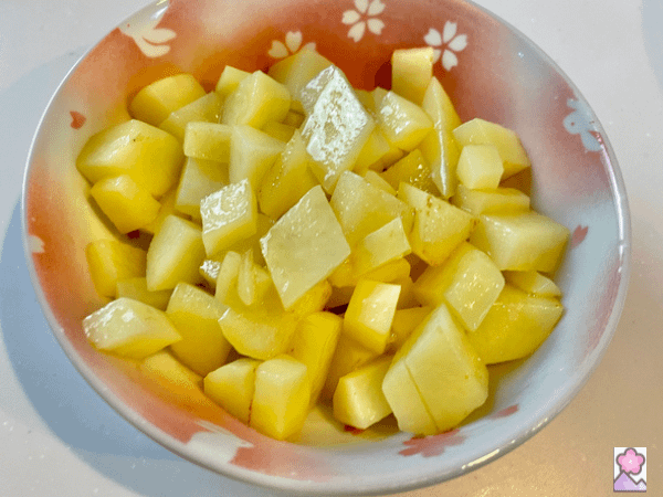 Diced cooked potatoes in a bowl with cherry blossom patterns
