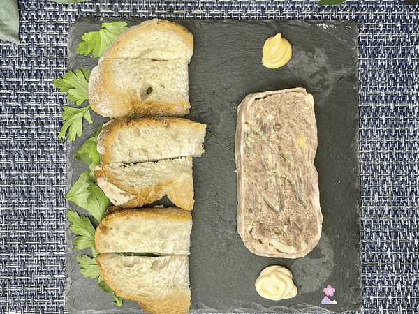 A slice of Prime Rib Terrine with toast points. There is a dollop of mustard and a dollop of mayonnaise as well.