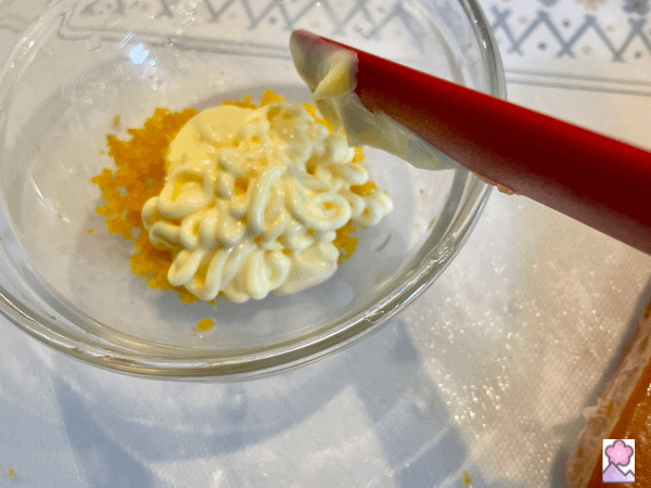 Mixing Karasumi and mayonnaise in a glass bowl with a thin spatula