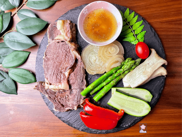 Boneless Ribeye Roast on a plate with vegetables on a wooden table