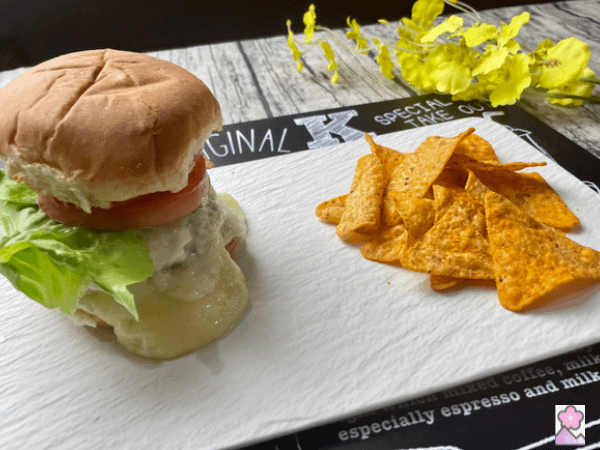 Steamed Cheeseburgers served on a ceramic tray with tortilla chips. Flowers are in the background