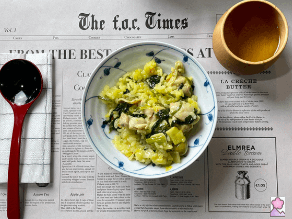Chicken and Olive Paella in a bowl with a spoon on the left and a wooden cup of tea on the right