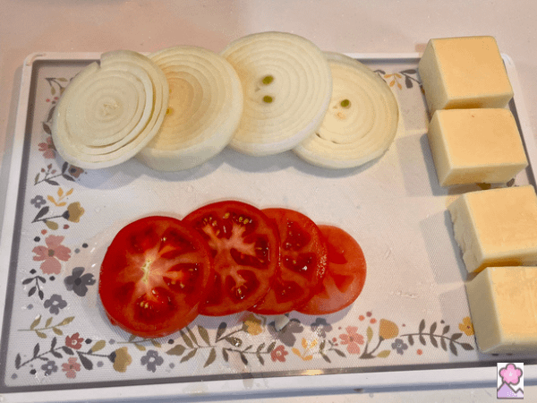 Cheese, onion, tomato each cut in four pieces on a cutting board